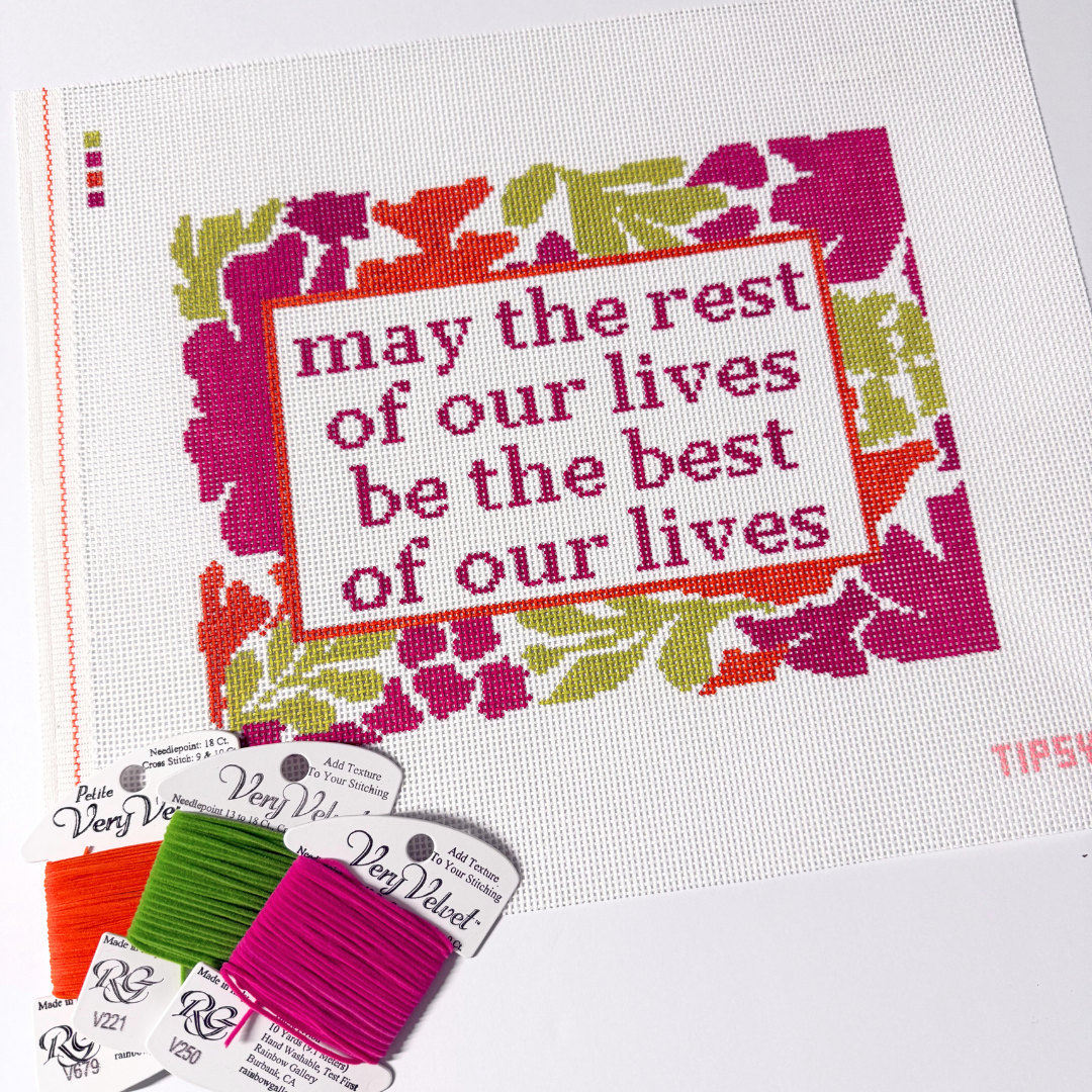 Needlepoint Kit project with floral design and motivational quote, surrounded by embroidery threads.