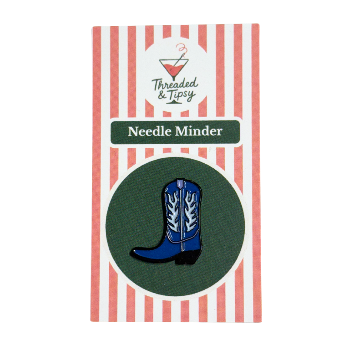 Blue cowboy boot needle minder on striped packaging with &