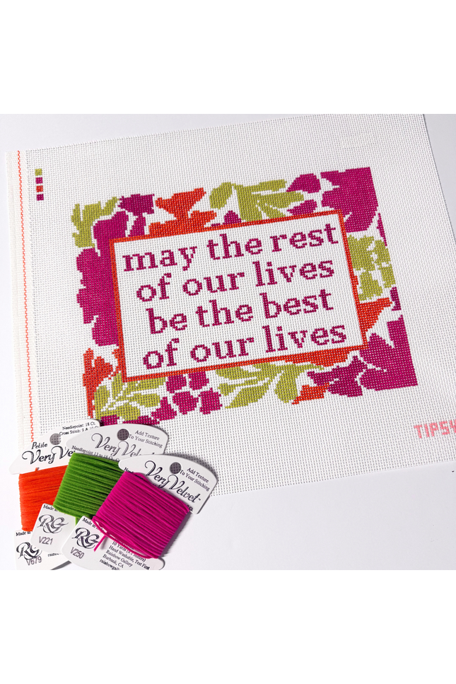Needlepoint Kit project with floral design and motivational quote, surrounded by embroidery threads.