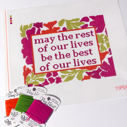Needlepoint Kit project with floral design and motivational quote, surrounded by embroidery threads.