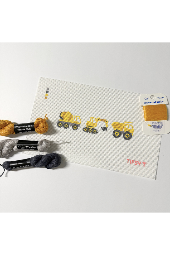 Needlepoint kit with construction-themed design, yarn, and a label on a white background