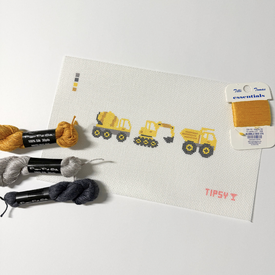 Needlepoint kit with construction-themed design, yarn, and a label on a white background