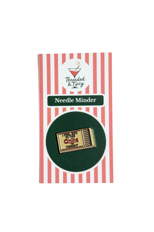 Gold matchbox-shaped needle minder on striped packaging with 'Threaded & Tipsy' branding.