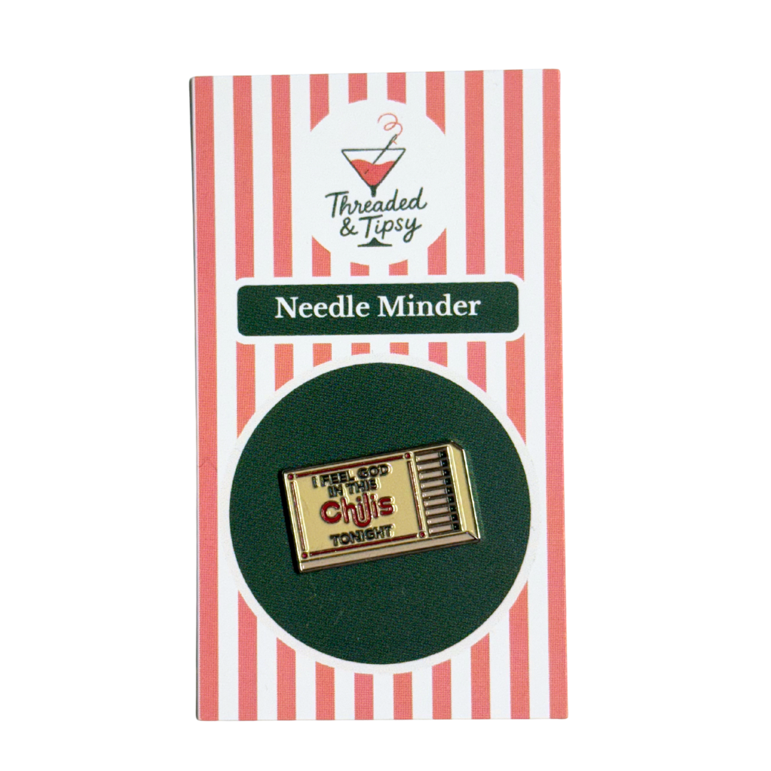 Gold matchbox-shaped needle minder on striped packaging with &