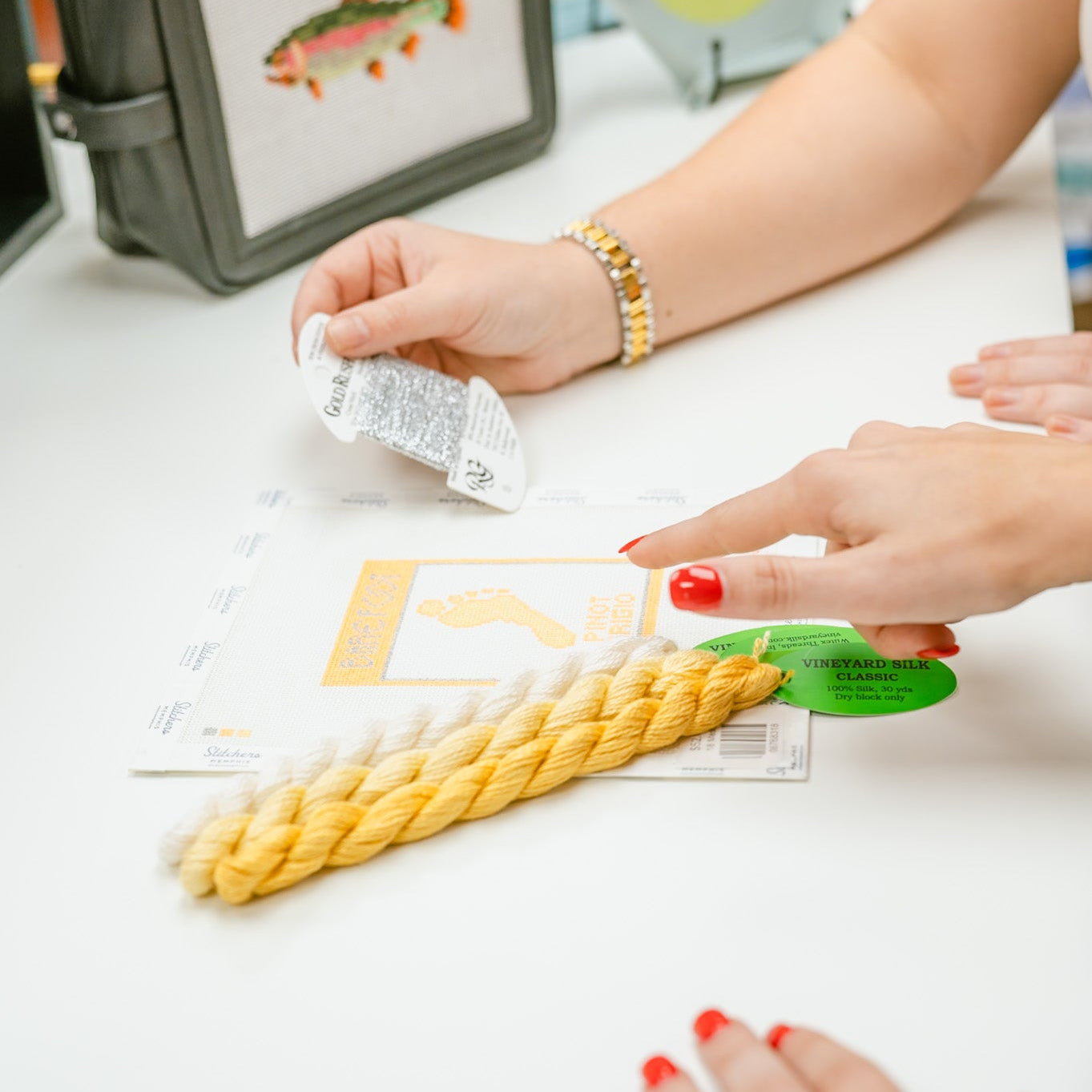 Person working with craft materials on a table, including a small bag with a fish illustration.