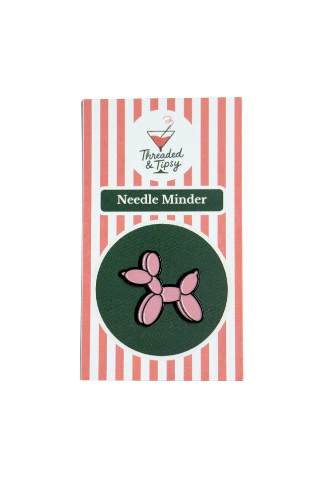 Pink balloon dog needle minder on striped packaging with 'Threaded & Tipsy' branding