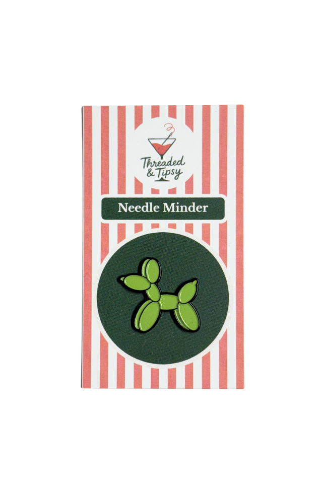 Green balloon dog needle minder on striped packaging with 'Threaded & Tipsy' branding.
