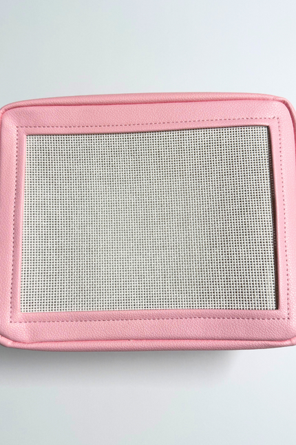 Pink needlepoint stitchable bag with a mesh panel on a light gray background