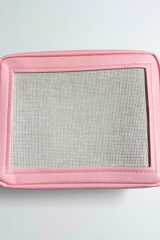 Pink needlepoint stitchable bag with a mesh panel on a light gray background