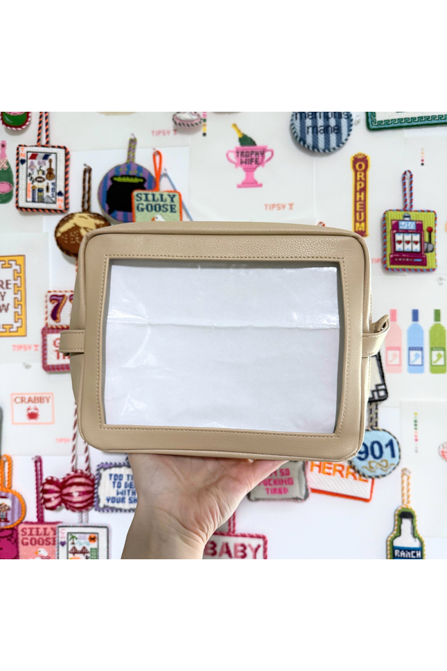 Beige needlepoint self-finishing pouch held in front of a colorful background with various designs and text.